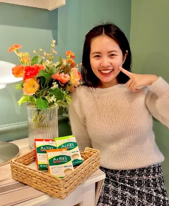 A KOC pointing at her cheek beside a basket of Mentholatum Acnes patch packs.